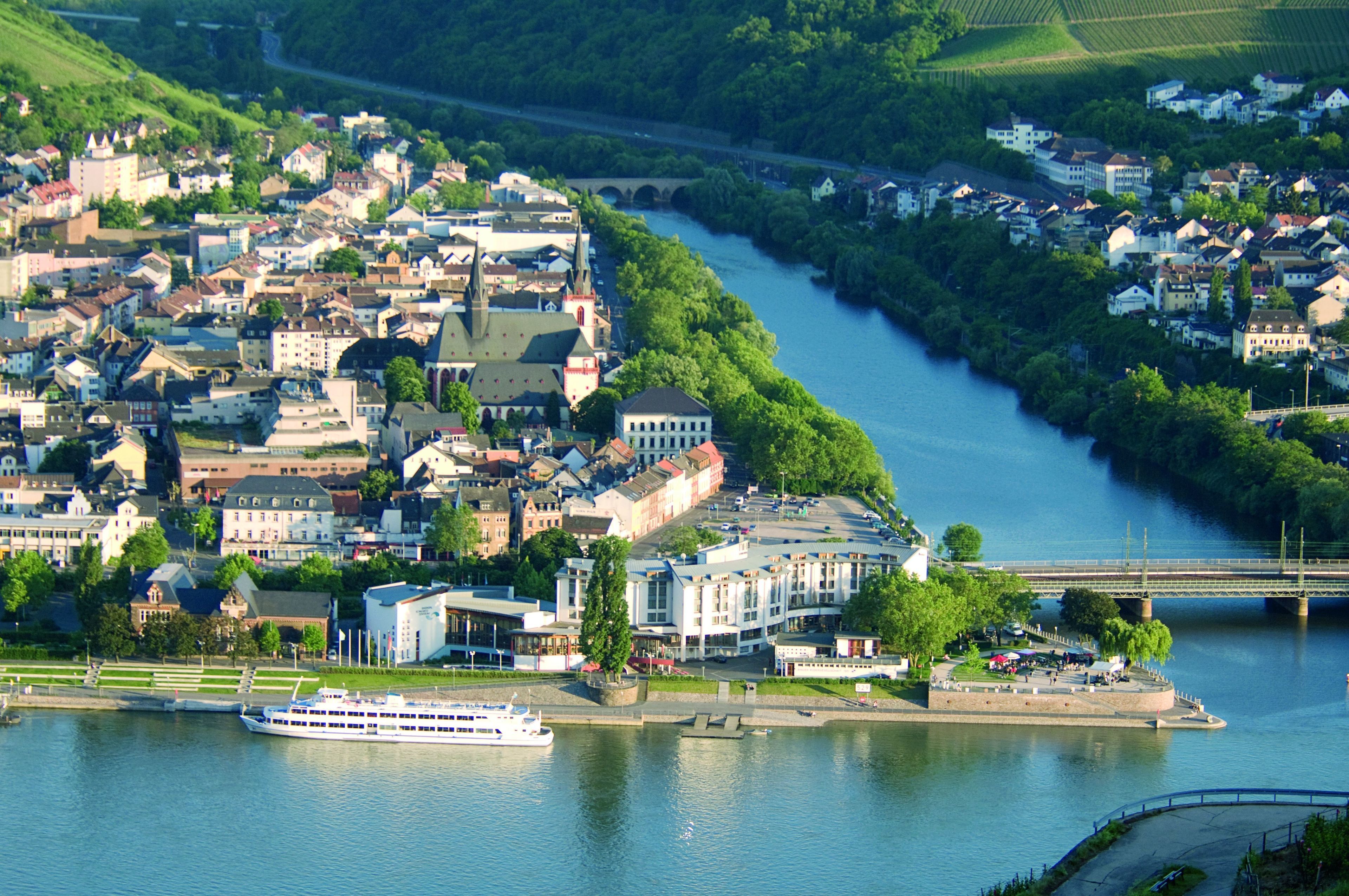 A riverside town with a prominent white cruise ship docked at the waterfront.