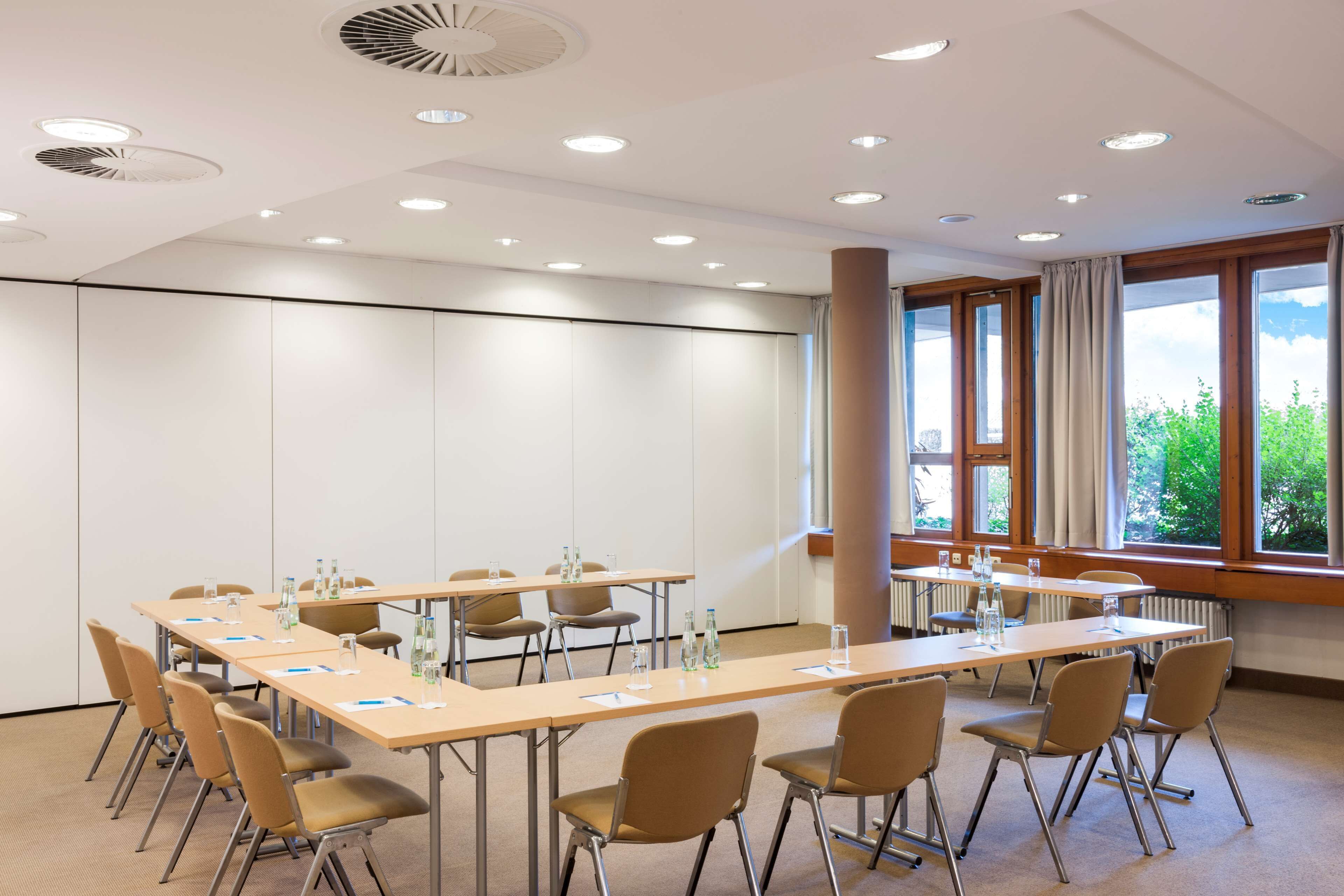 A conference room with a long table, chairs, and a large window with curtains.