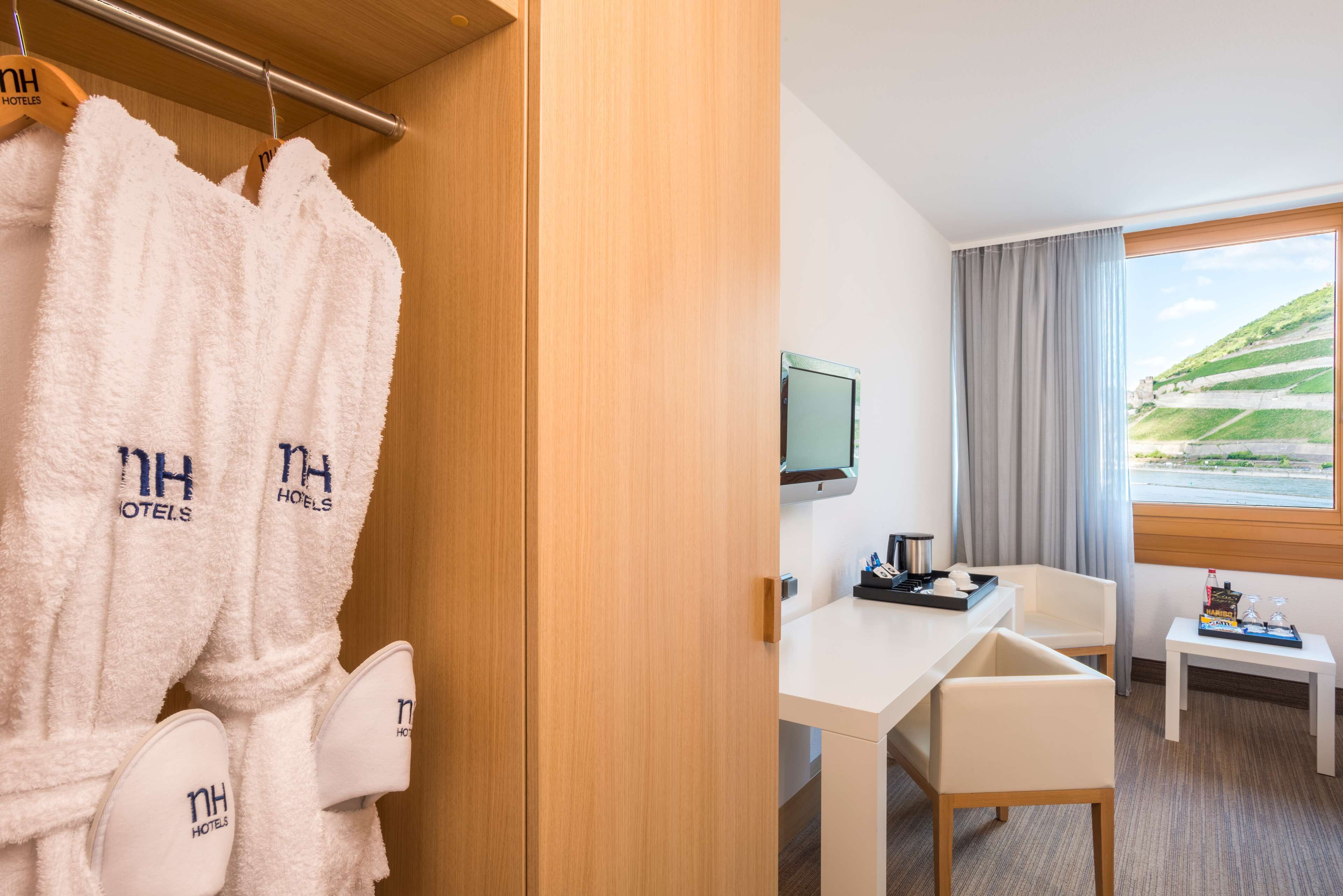 Habitación de hotel con armario de madera, un escritorio con silla, televisión y vistas a un paisaje verde a través de la ventana.