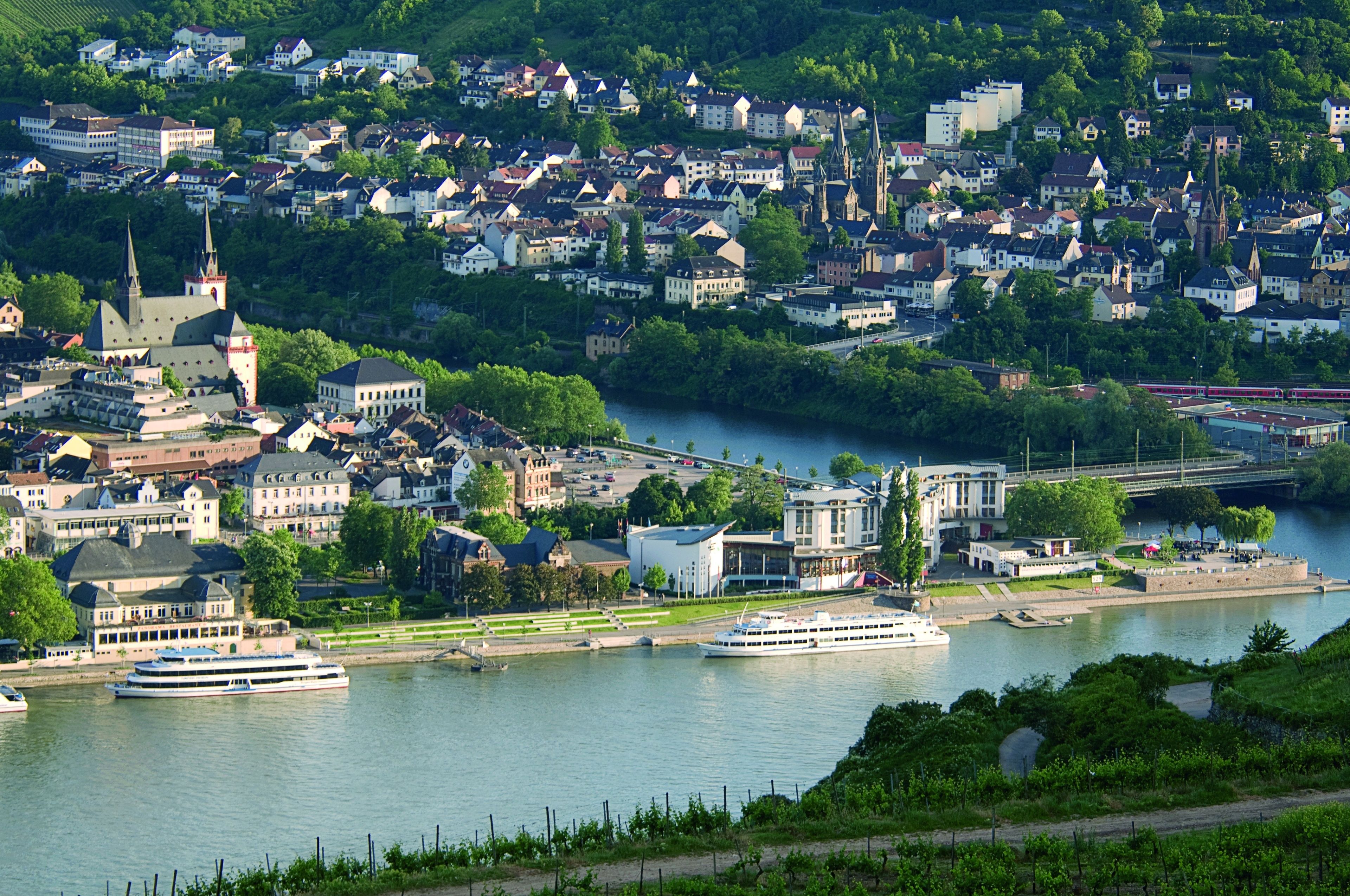 A riverside town with historic buildings, a prominent church, and a ferry dock.