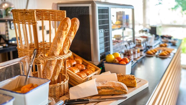 Una barra libre con diversos alimentos, incluyendo pan, pasteles y frutas.
