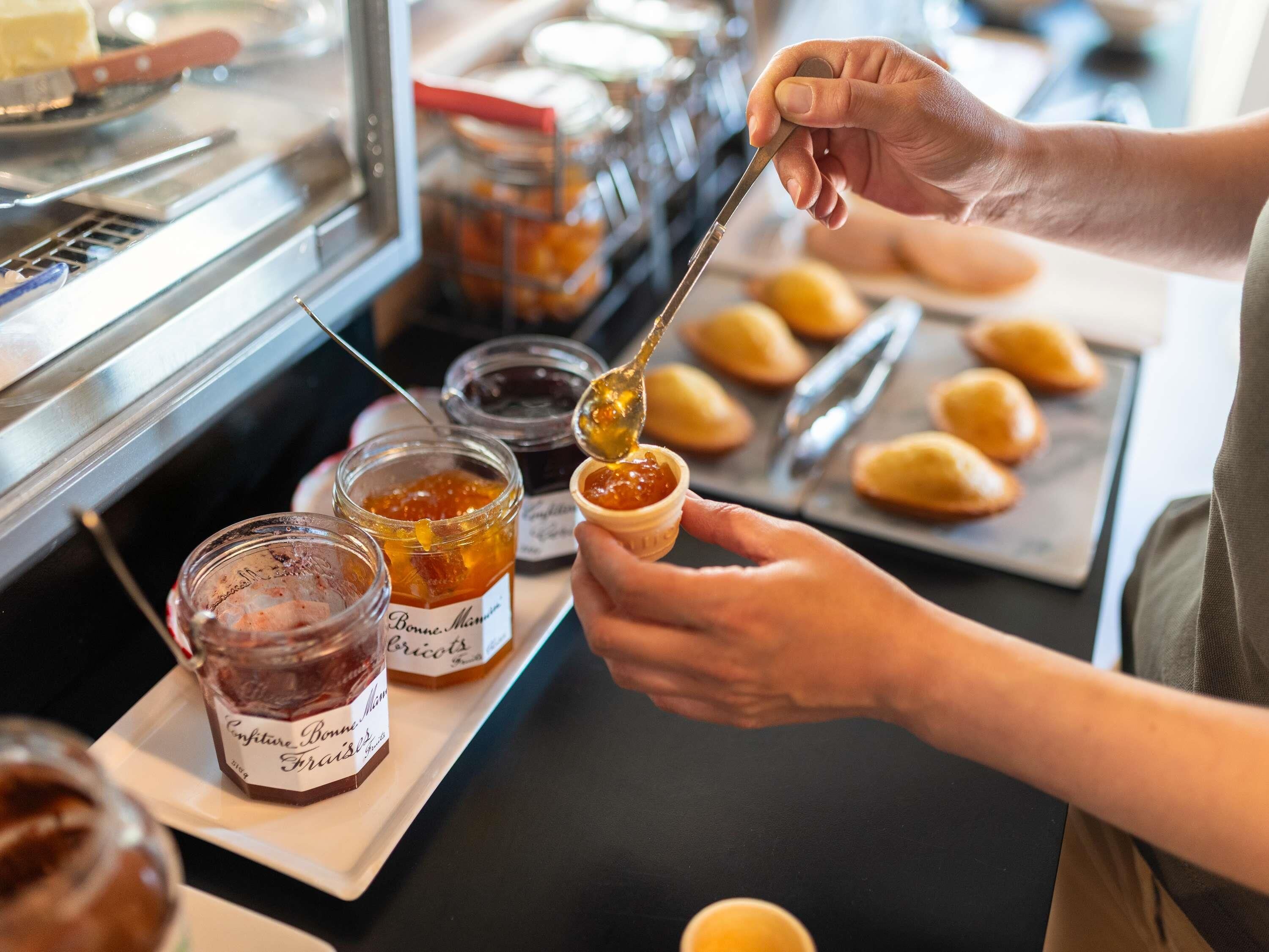 A person preparing food, specifically spreading jam on a pastry.
