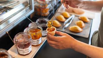 A person preparing food, specifically spreading jam on a pastry.