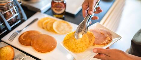 A person serving pancakes on a plate.
