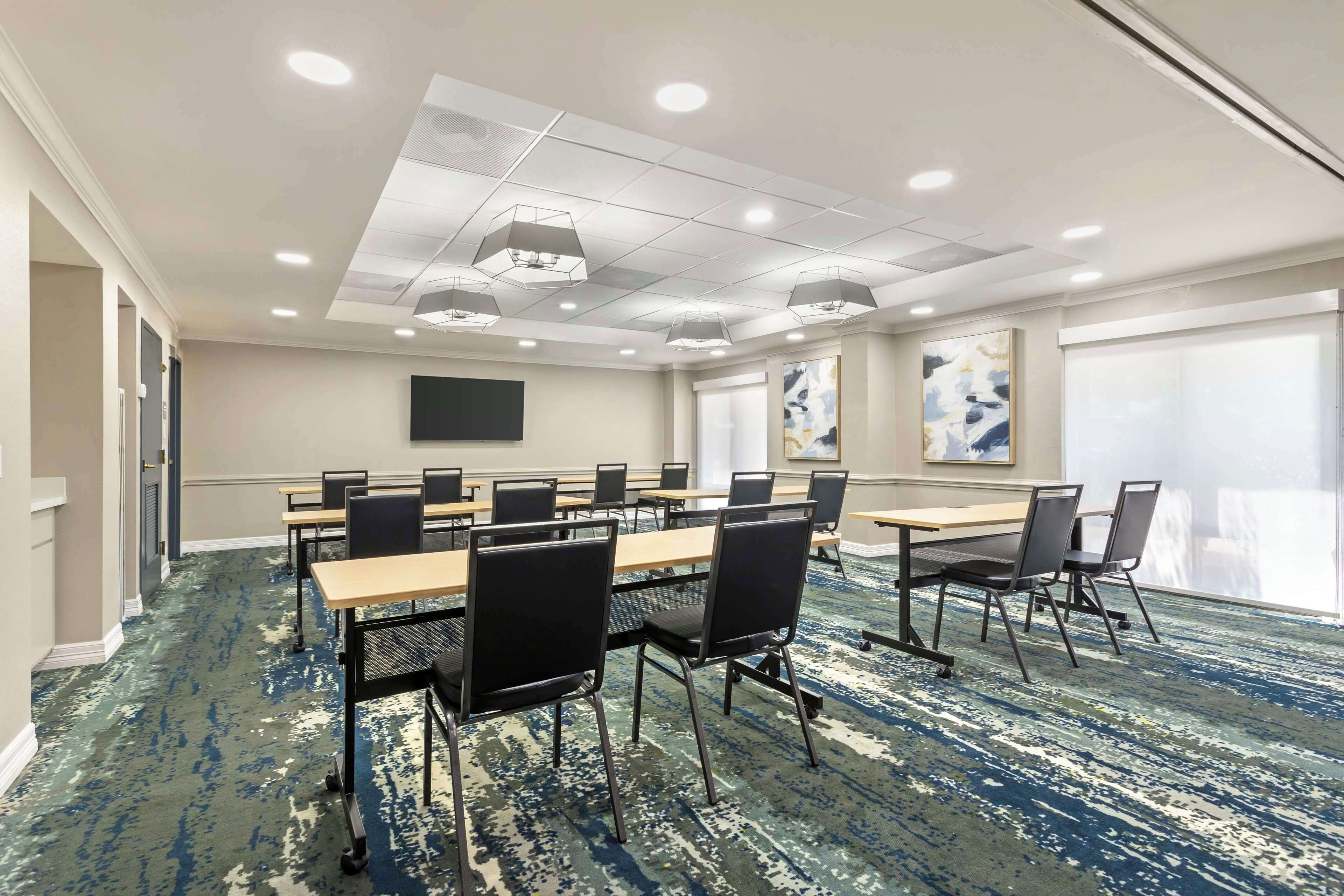 A conference room with tables and chairs, a flat-screen TV, and artwork on the walls.