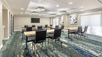 A conference room with tables and chairs, a flat-screen TV, and artwork on the walls.