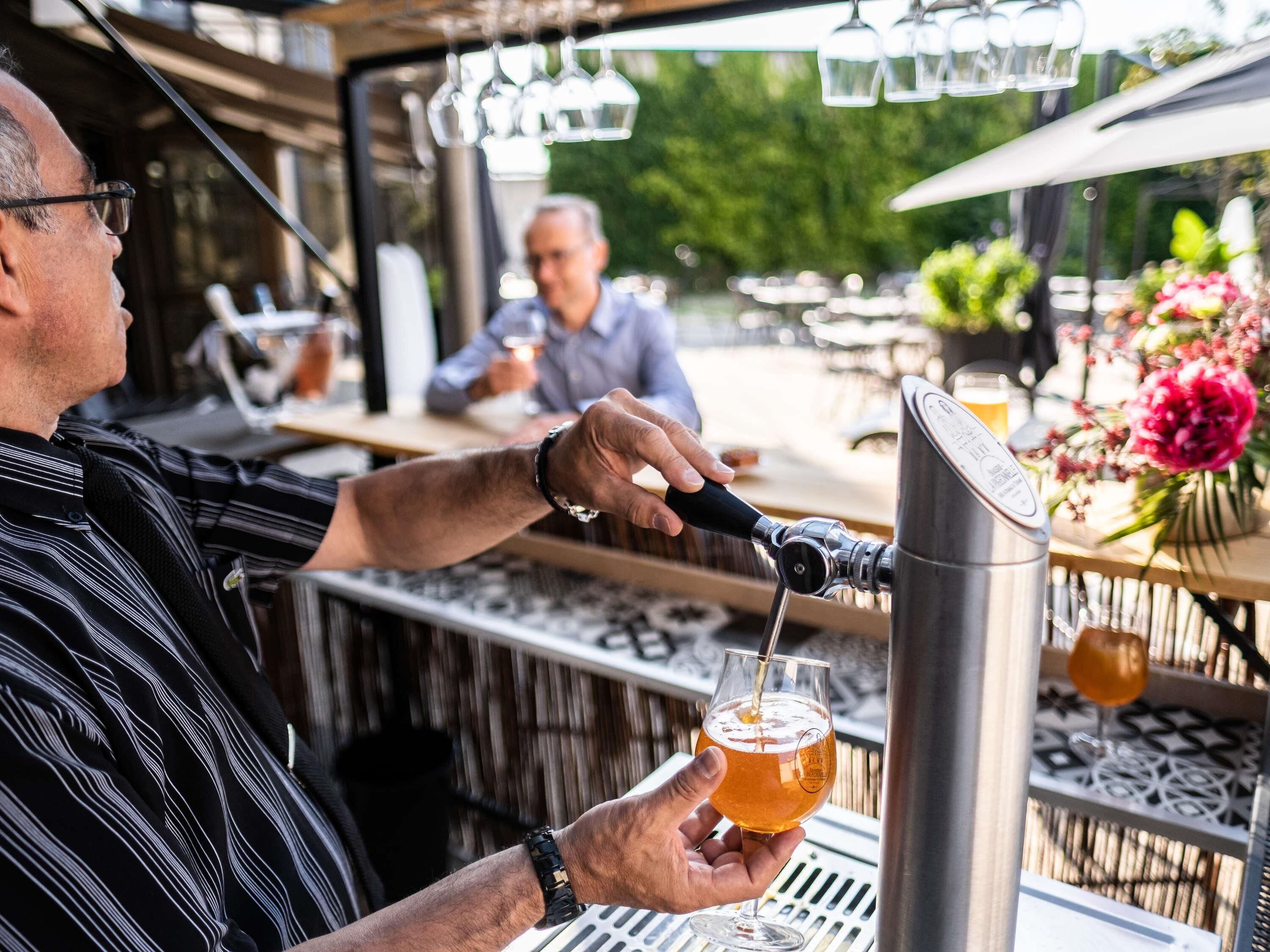 En bardisk där en person häller upp en drink i ett glas.