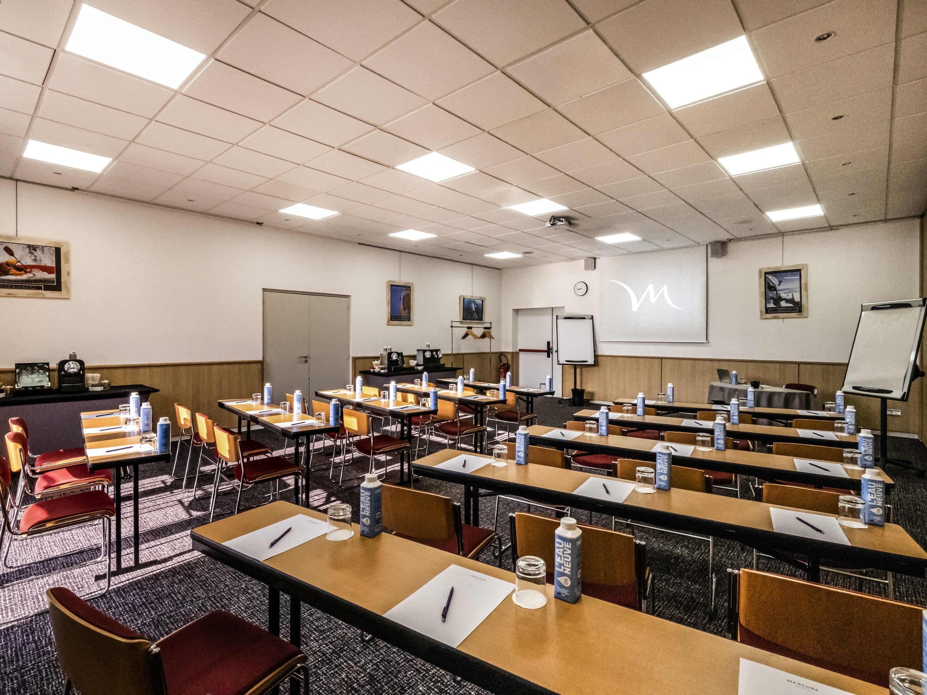 A conference room with tables, chairs, a whiteboard, and a clock on the wall.