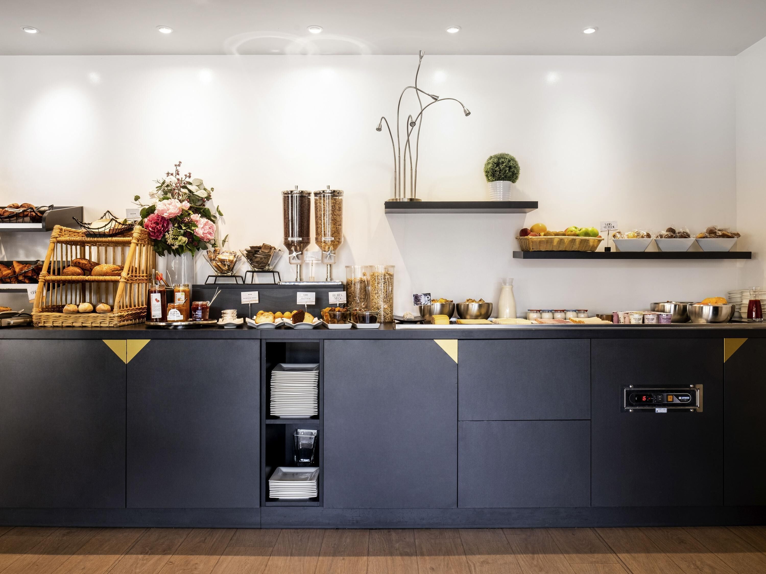 Montaje moderno de buffet con diferentes opciones de comida, una estación de café y un reloj digital.