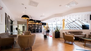 A spacious lobby with modern furniture, a staircase, and a large window providing natural light.