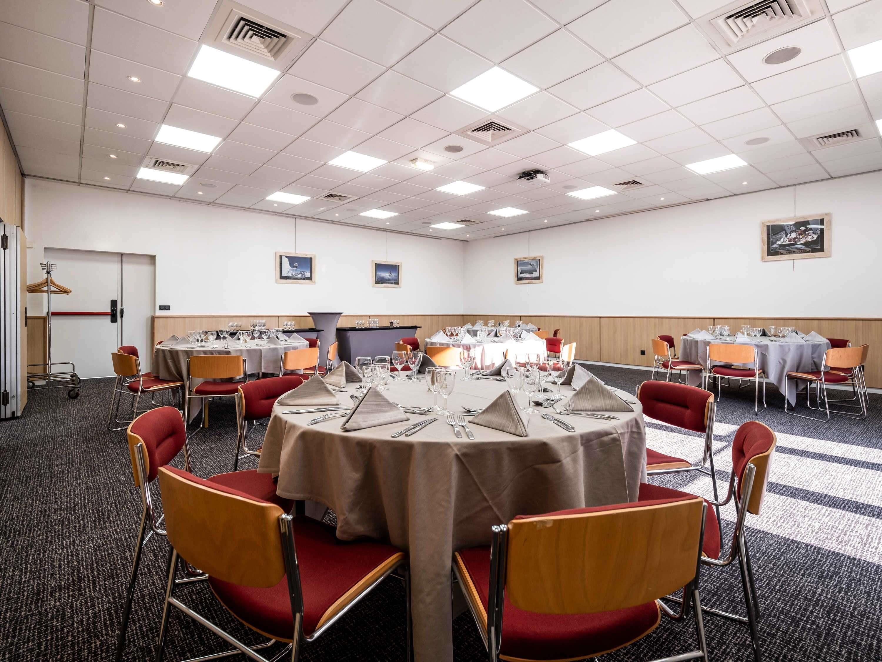 A conference room with round tables, chairs, and a carpeted floor.