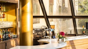 Eine moderne Bar mit einer gebogenen Theke, einer großen, goldenen Säule und Blick durch große Fenster.
