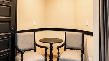 A corner room with a round table and two chairs, an air conditioning unit, and a door.