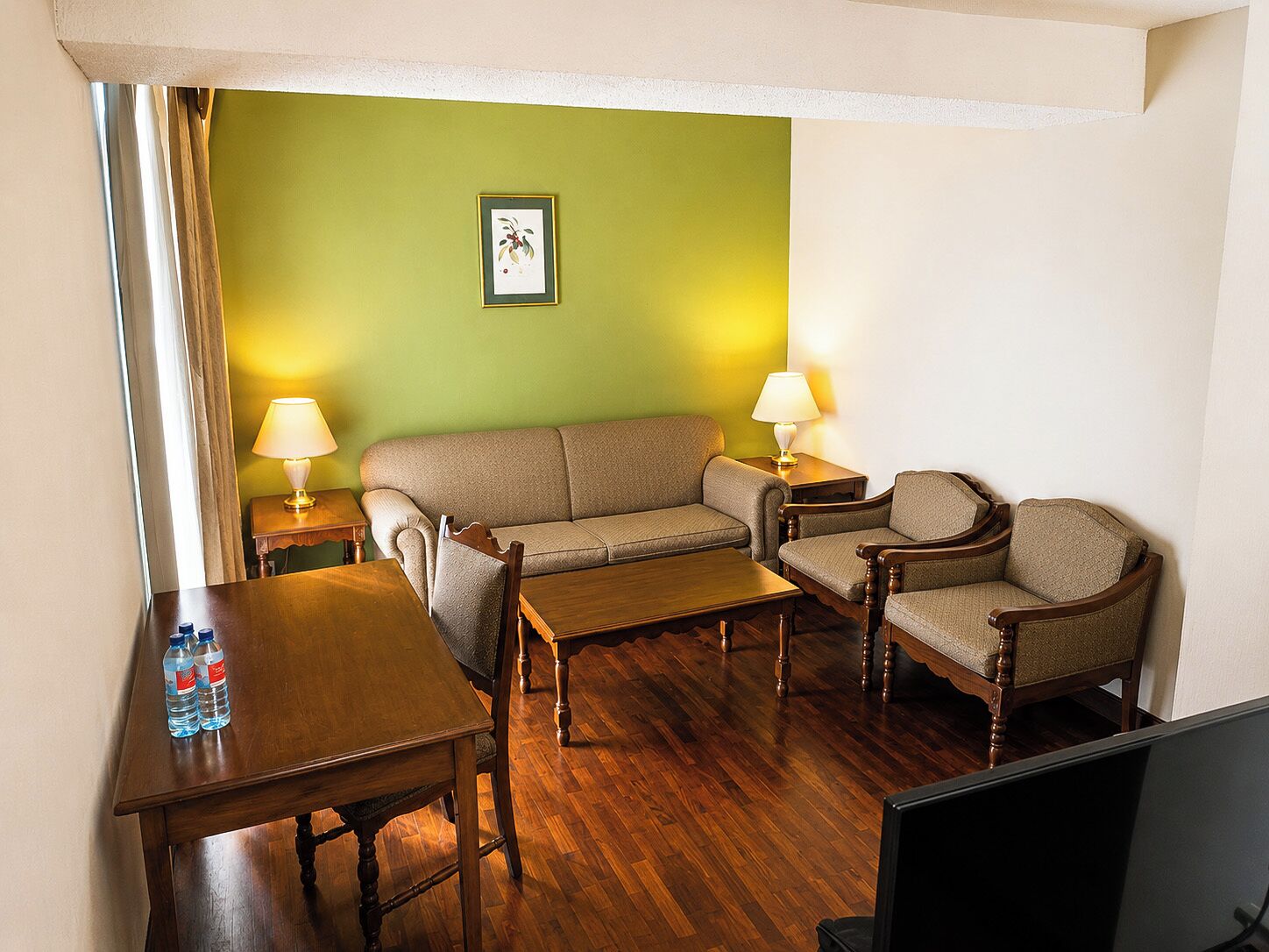 A room with a wooden table, two chairs, a sofa, and two lamps.