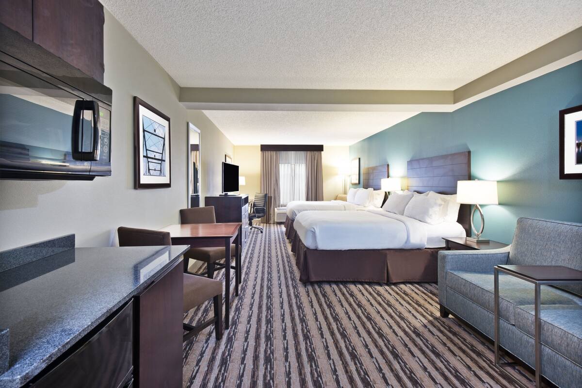 A hotel room with a bed, a desk, a chair, a sofa, and a TV.