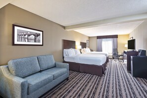 Quarto de hotel com sofá, duas camas, mesa de escritório e televisão.