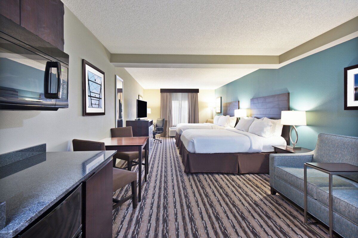 A hotel room with a bed, a desk, a chair, a sofa, and a TV.
