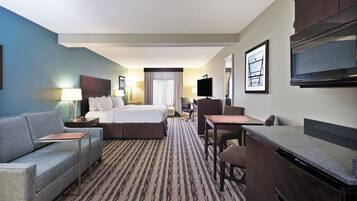 A hotel room with a bed, a desk, a chair, a sofa, and a television.