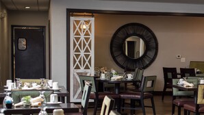 Un espace repas avec des tables dressées pour le service, un grand miroir au mur et un élément de séparation décoratif.