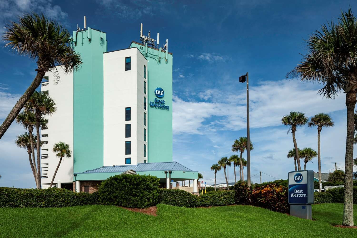 A Best Western hotel with a prominent tower, surrounded by palm trees and a well-maintained lawn.