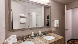 Une salle de bain avec deux lavabos, un grand miroir et un espace douche.