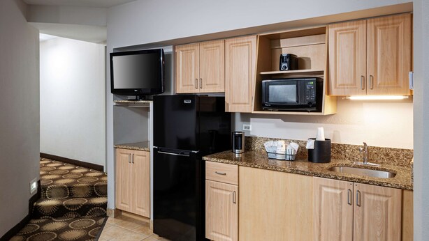 A compact kitchen with a refrigerator, microwave, and a flat-screen TV.