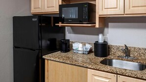 Une cuisine compacte équipée d’un réfrigérateur, d’un four à micro-ondes, d’une machine à café et d’un évier.