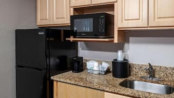 Cocina pequeña equipada con refrigerador, microondas, cafetera y pileta.