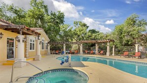 Un espace piscine comprenant un jacuzzi, des chaises longues et une pergola.