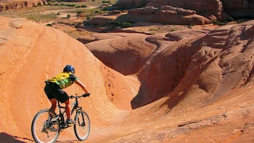 Una persona montando en bicicleta sobre terreno rocoso, con una vista despejada del paisaje circundante.