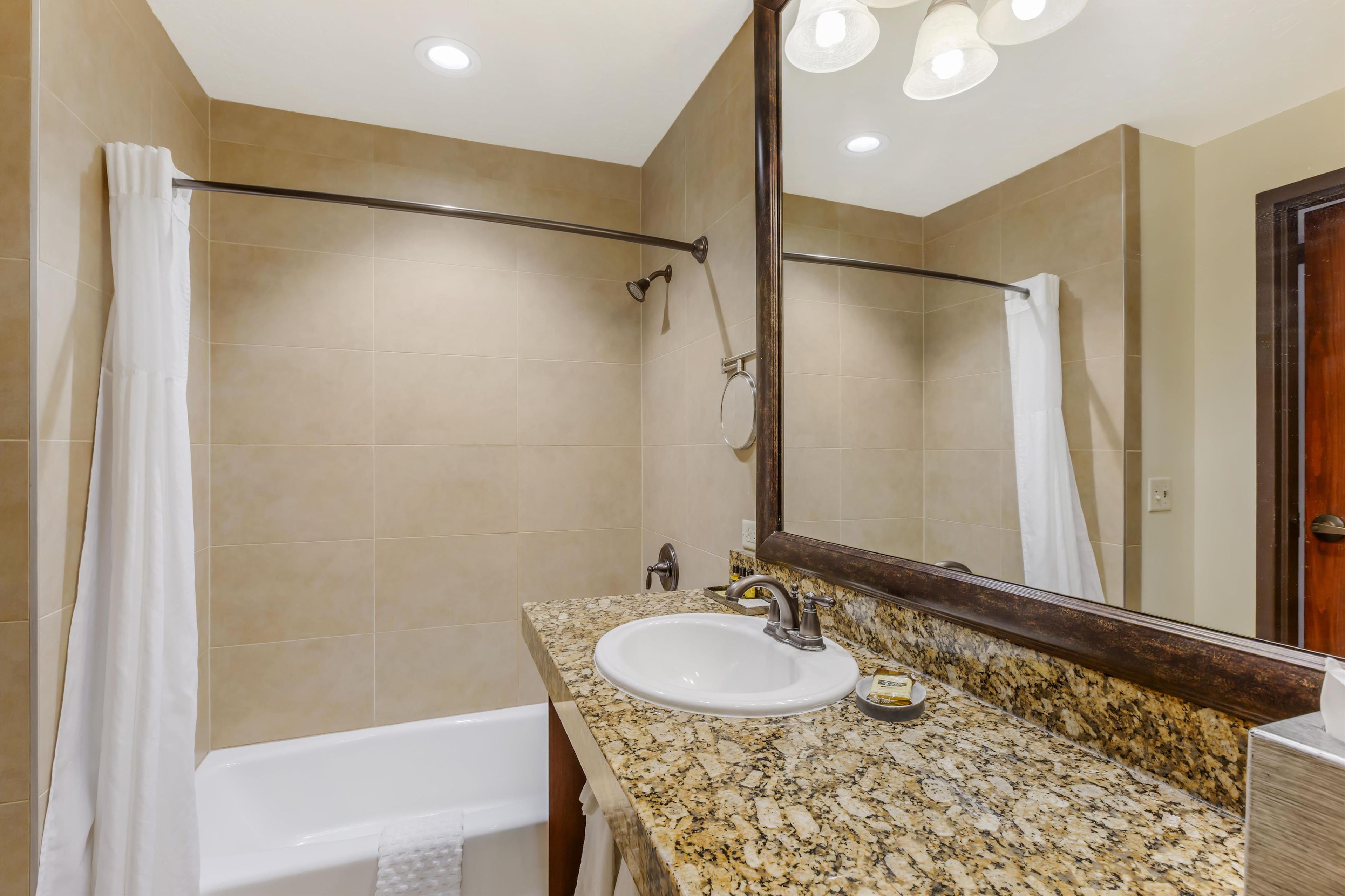 Une salle de bain avec un lavabo blanc, un miroir et un rideau de douche.