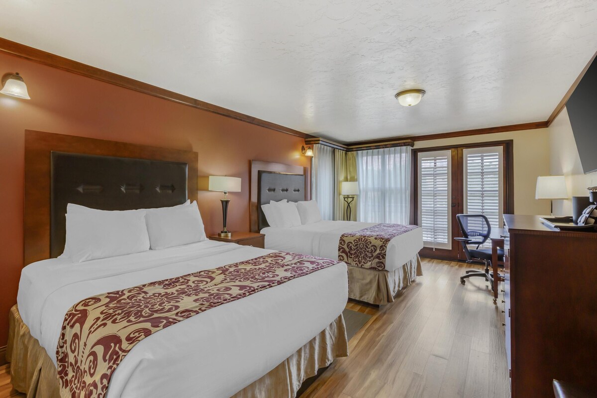 Habitación de hotel con dos camas, un escritorio y una silla.