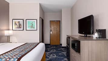 A hotel room with a bed, a television, a microwave, and a door leading to another room.