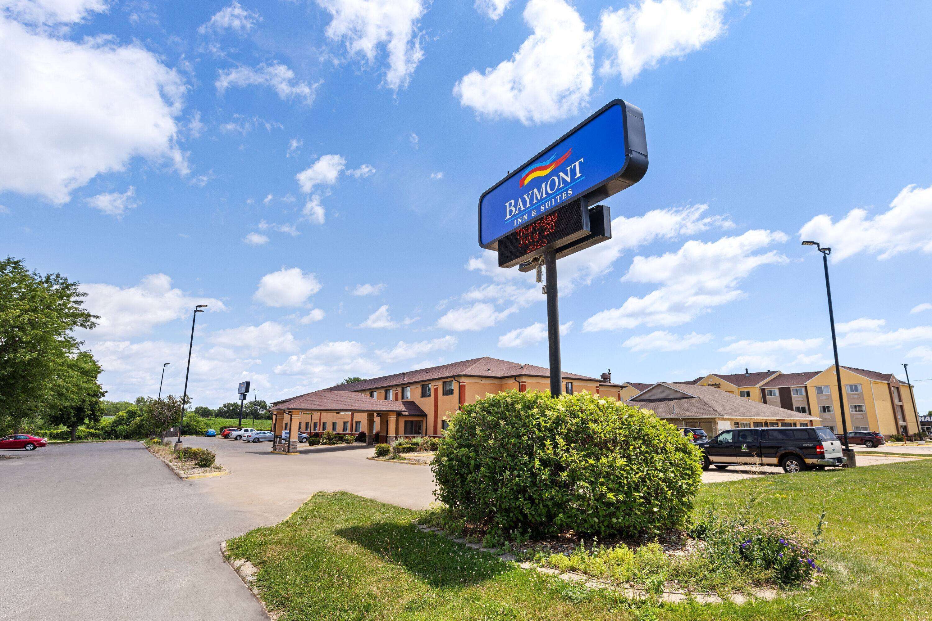 A Baymont Inn & Suites with a clear sky and a well-maintained lawn.