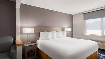 A hotel room with a large bed, two bedside tables, a desk, and a chair.
