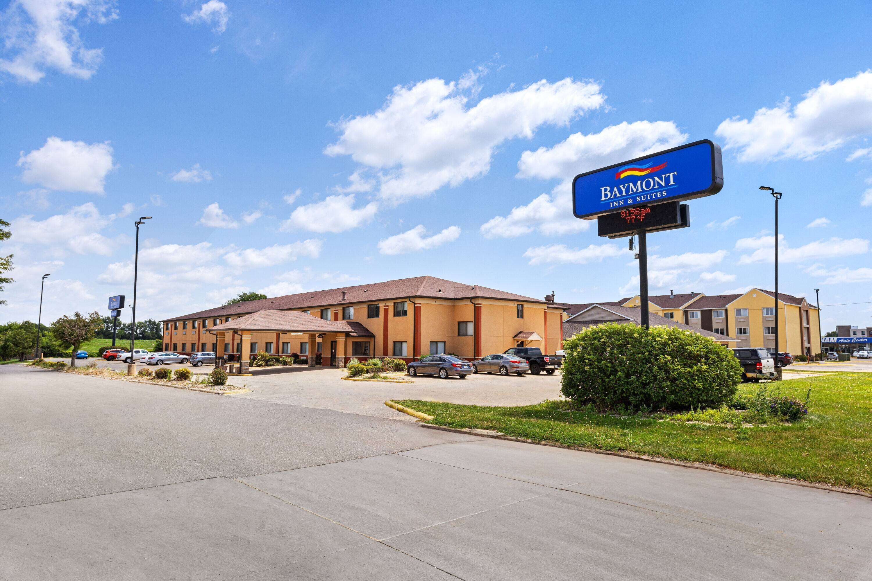 A Baymont Inn & Suites with a parking lot and a clear blue sky.