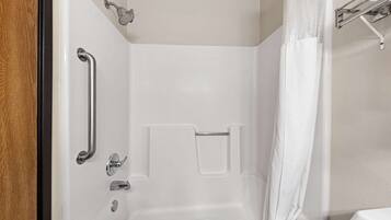 A bathroom with a shower, grab bars, and a towel rack.