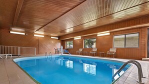 An indoor swimming pool with wooden walls, tiled floor, and a pool ladder.