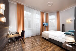 Una habitación de hotel con una cama, un escritorio, una silla, un televisor y un teléfono.
