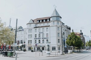 Un hotel histórico con un estilo arquitectónico europeo clásico, que presenta una destacada torre en esquina y una amplia entrada.