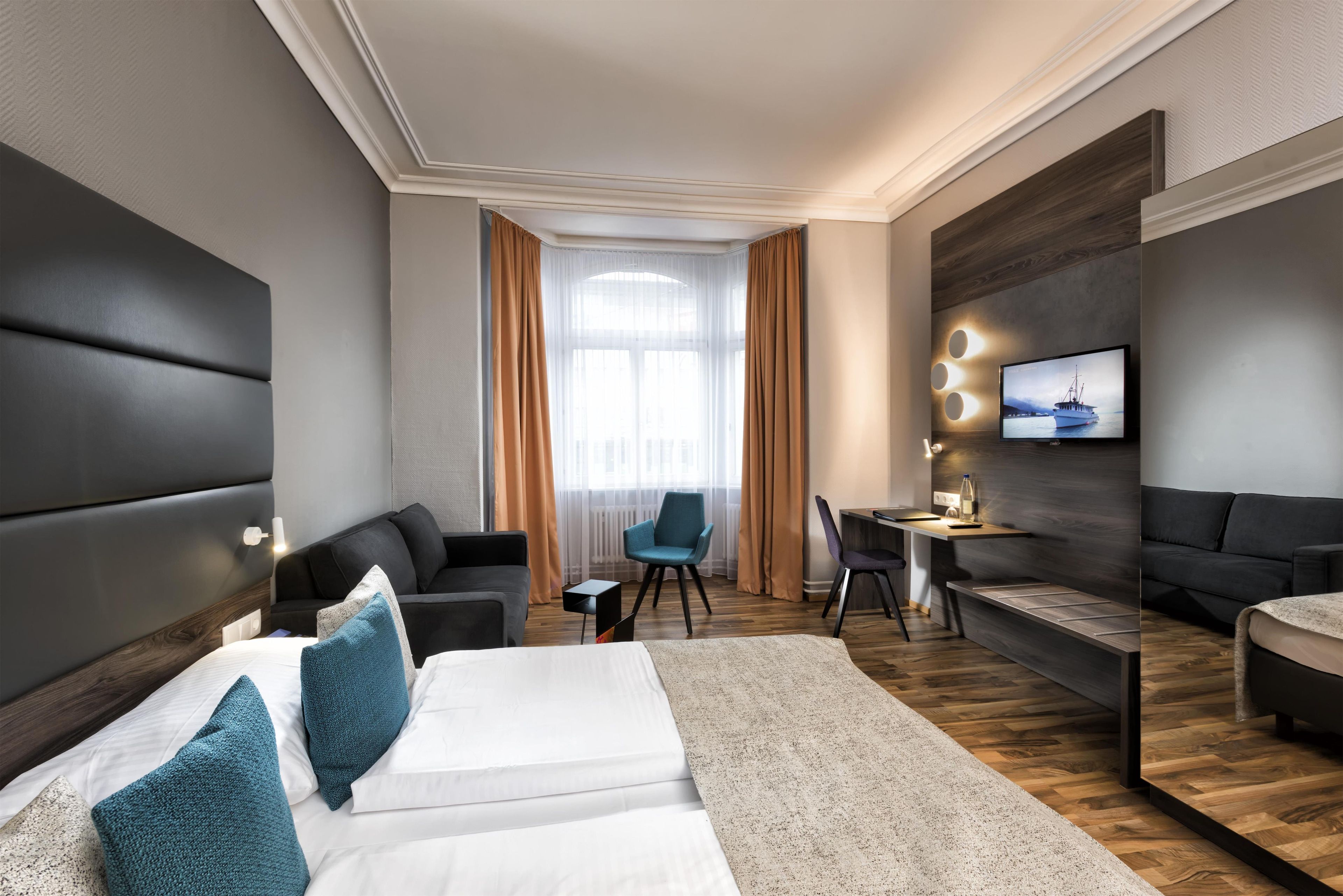 Une chambre d’hôtel moderne équipée d’un grand lit, d’un bureau, d’un canapé et d’une télévision.