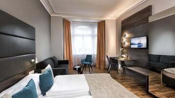 Une chambre d’hôtel moderne équipée d’un grand lit, d’un bureau, d’un canapé et d’une télévision.