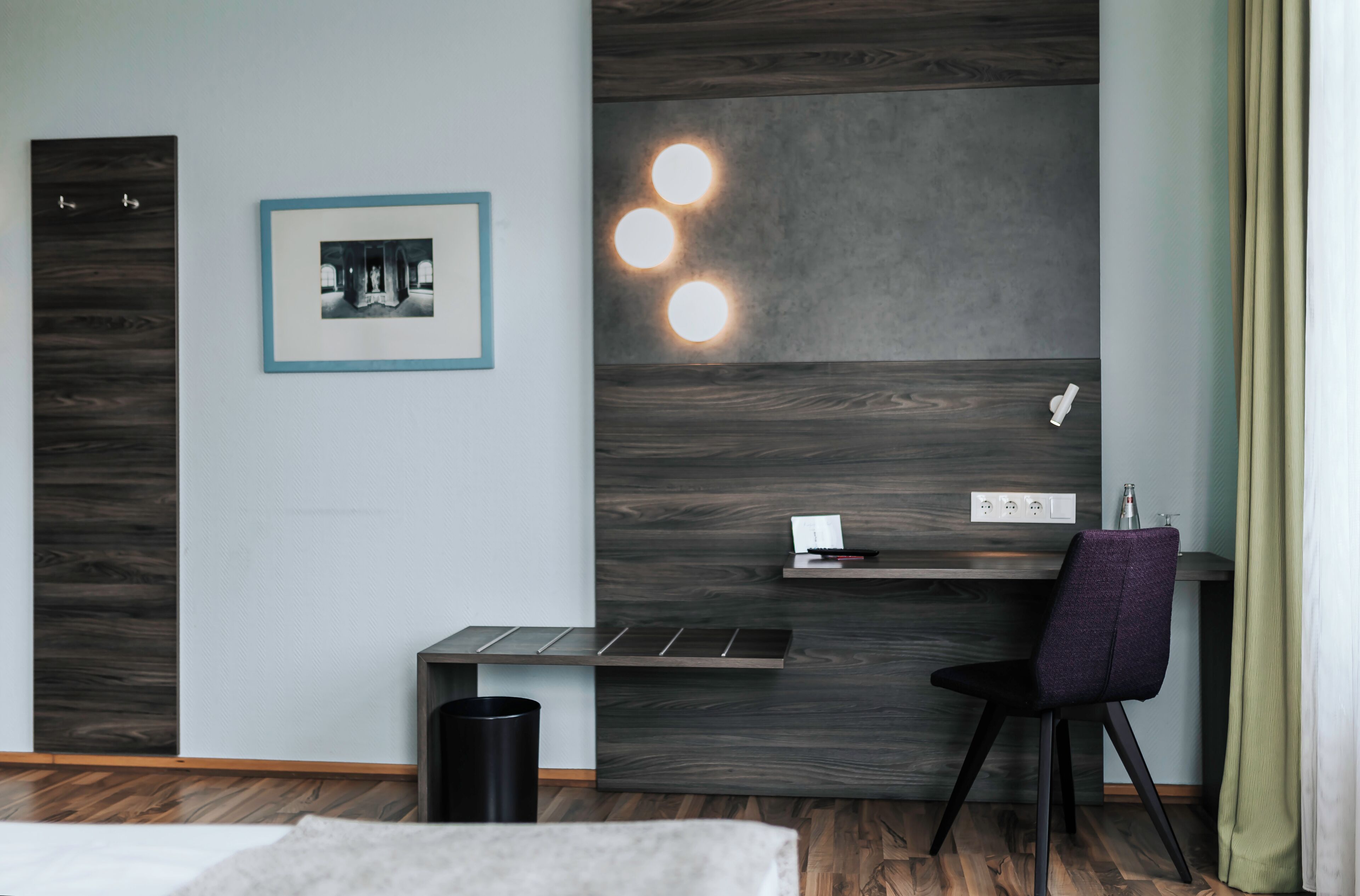 A modern room with a desk, chair, and a framed picture on the wall.