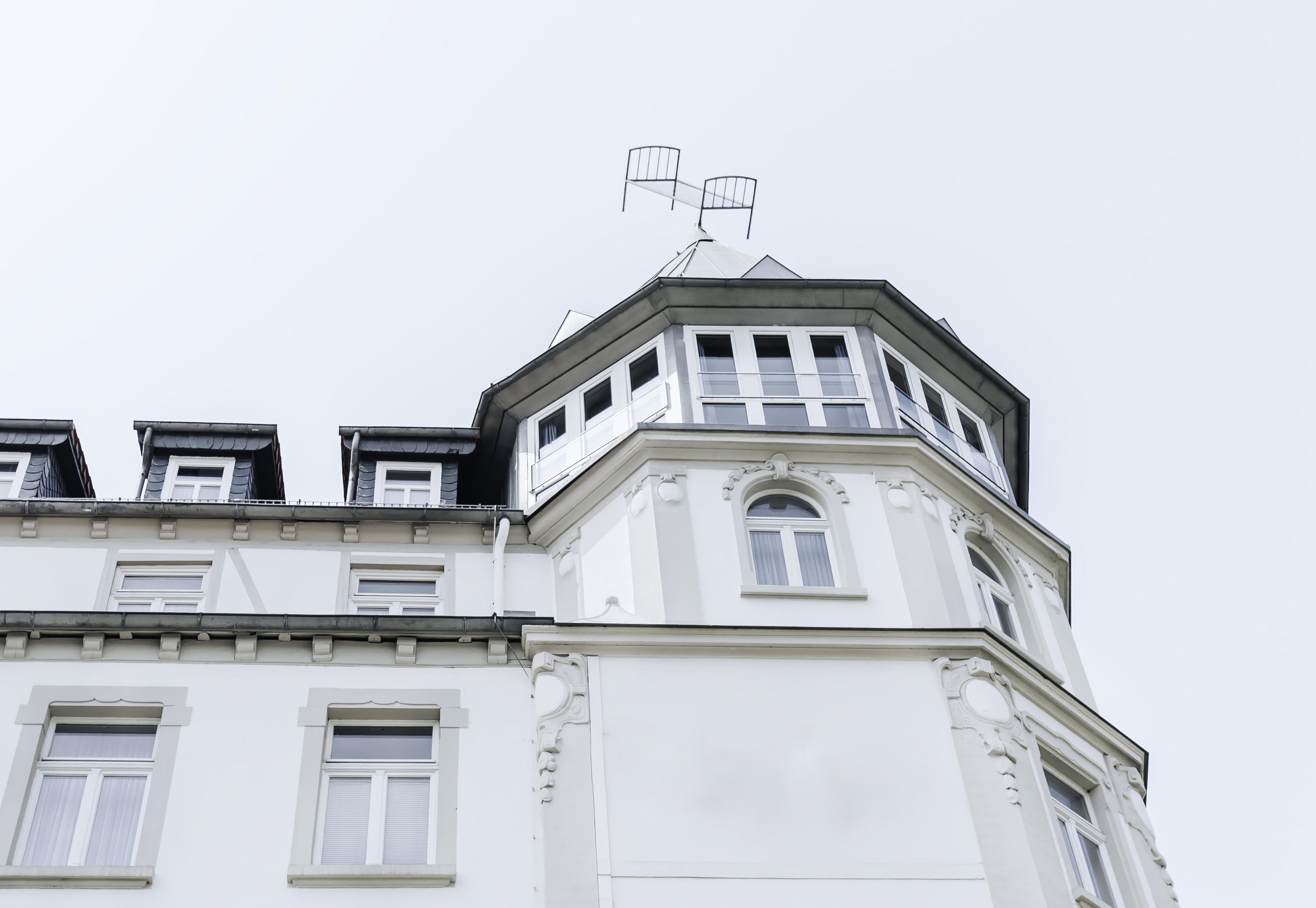 A corner of a building with a white facade, multiple windows, and a distinct architectural style with decorative moldings.