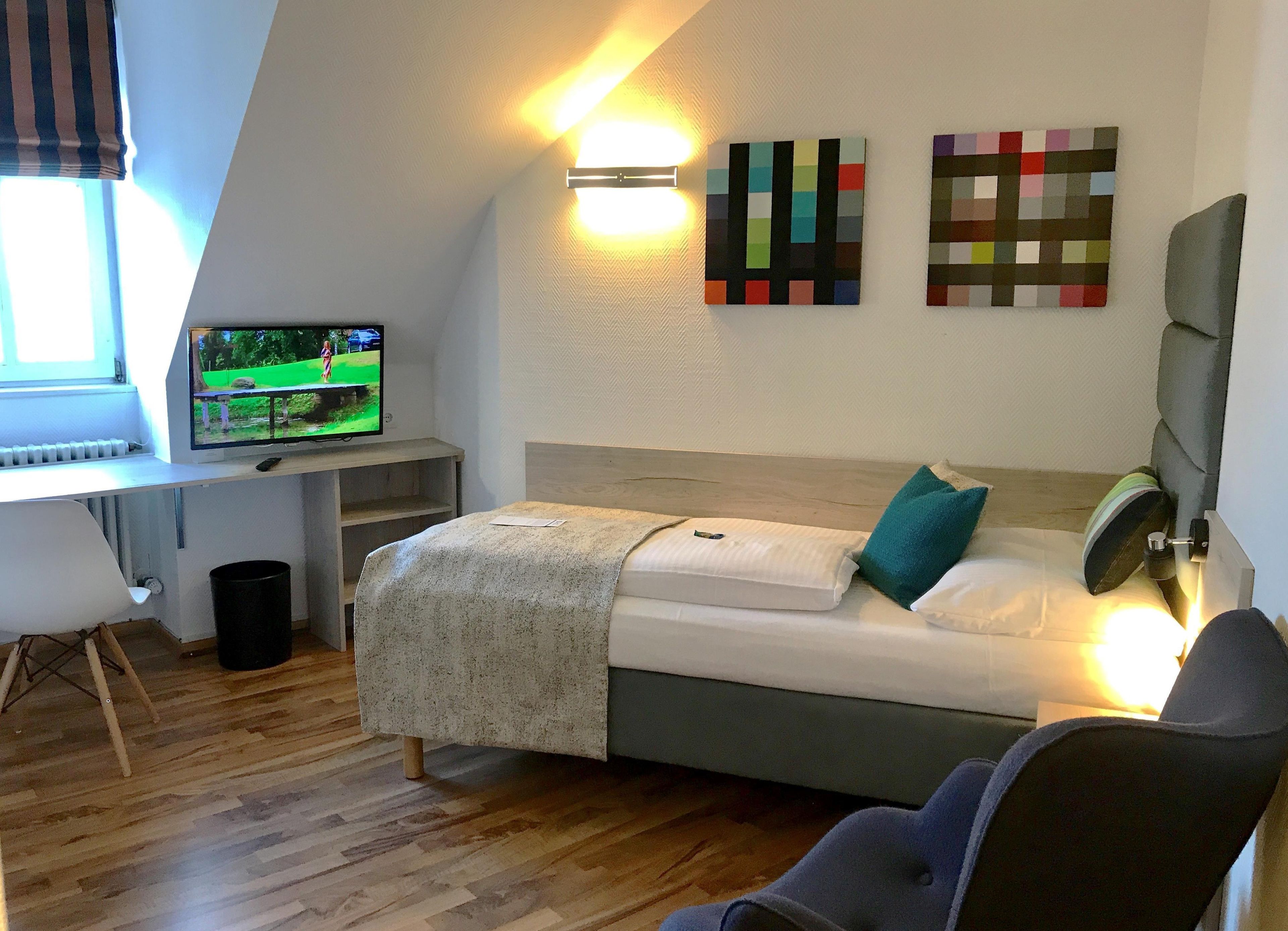 Un dormitorio con cama, escritorio, silla y televisor.