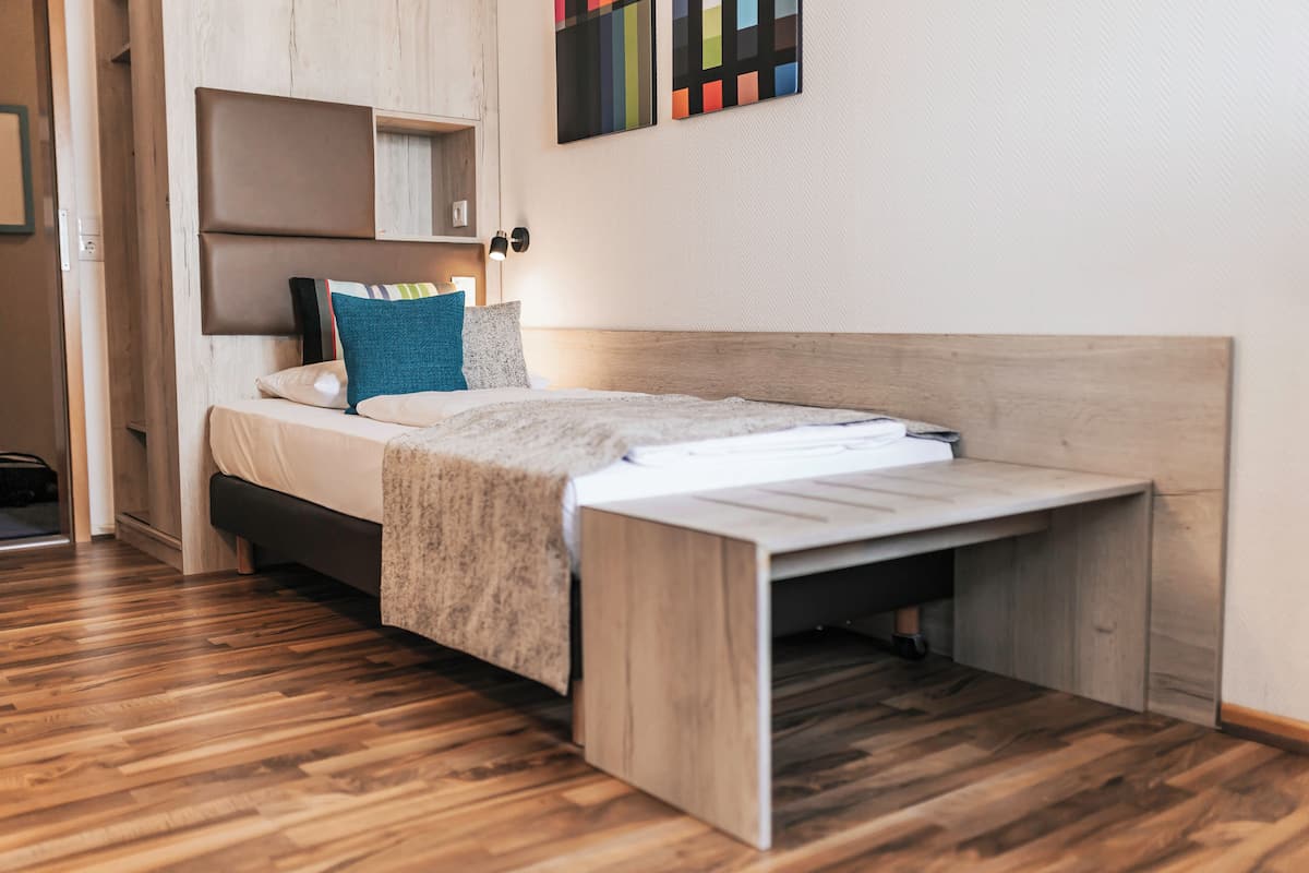 Quarto moderno com cama, cabeceira de madeira e escrivaninha embutida.