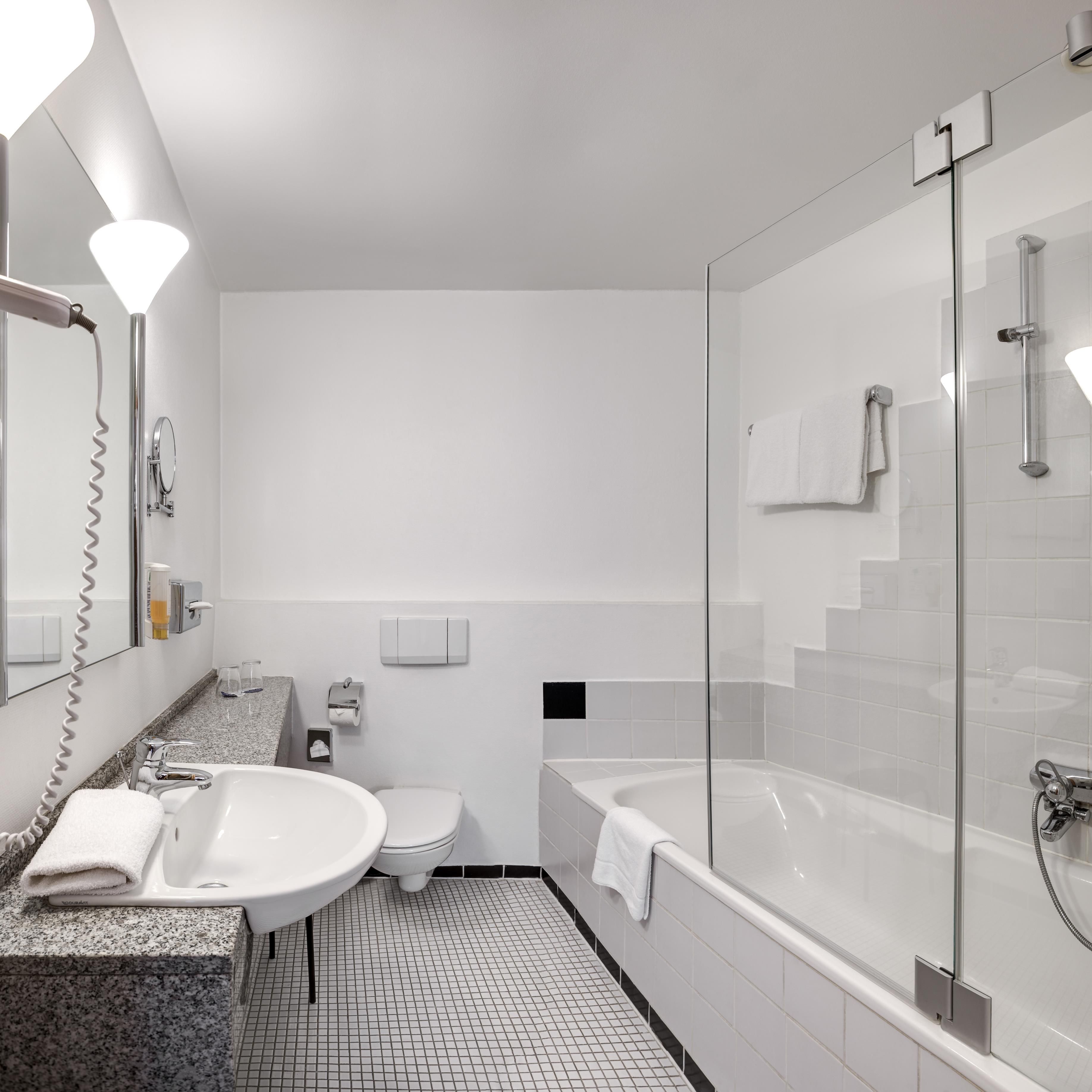 A modern bathroom with a glass-enclosed shower, a sink with a marble countertop, and a toilet.