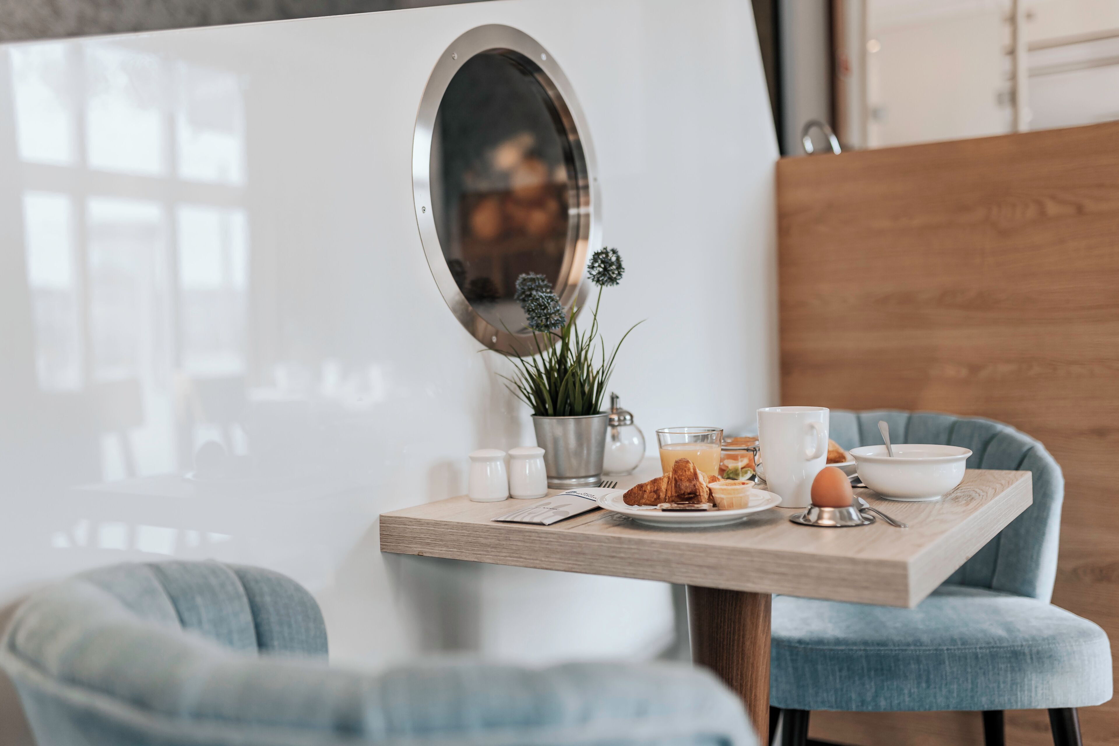 A breakfast table with a mirror, a plant, and various breakfast items.