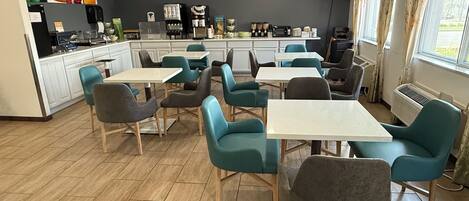 A modern cafe with a kitchen area, seating, and a TV screen.