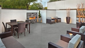An outdoor patio with a stone fireplace, wicker furniture, and decorative plants.